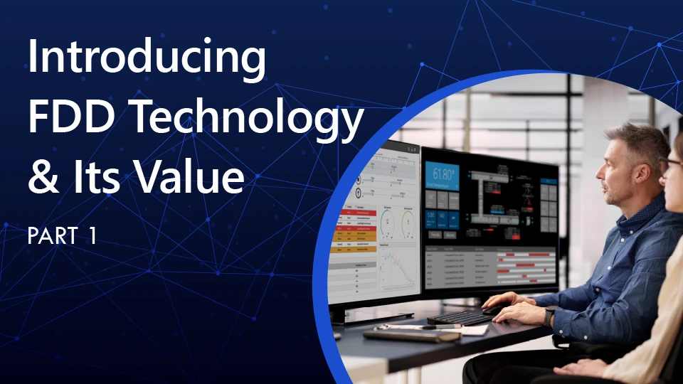 A man at a computer with a woman watching on is looking at a building's operational status on multiple computer screens.