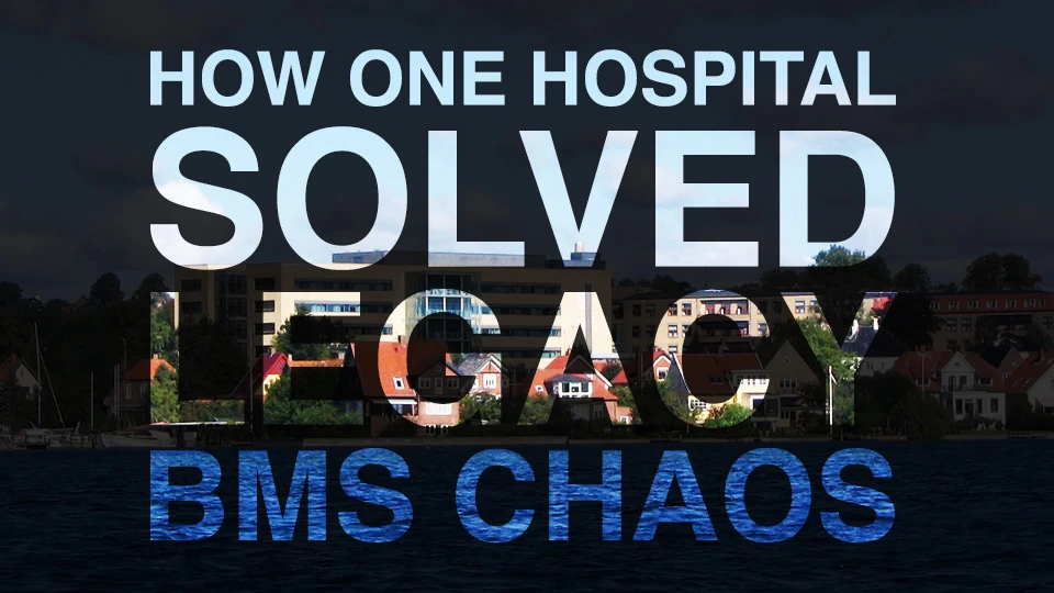 Bold text overlaid on a hospital building reads: ‘How One Hospital Solved Legacy BMS Chaos.’ The word ‘Legacy’ is highlighted with a cut-out effect showing the building and sky in the background.