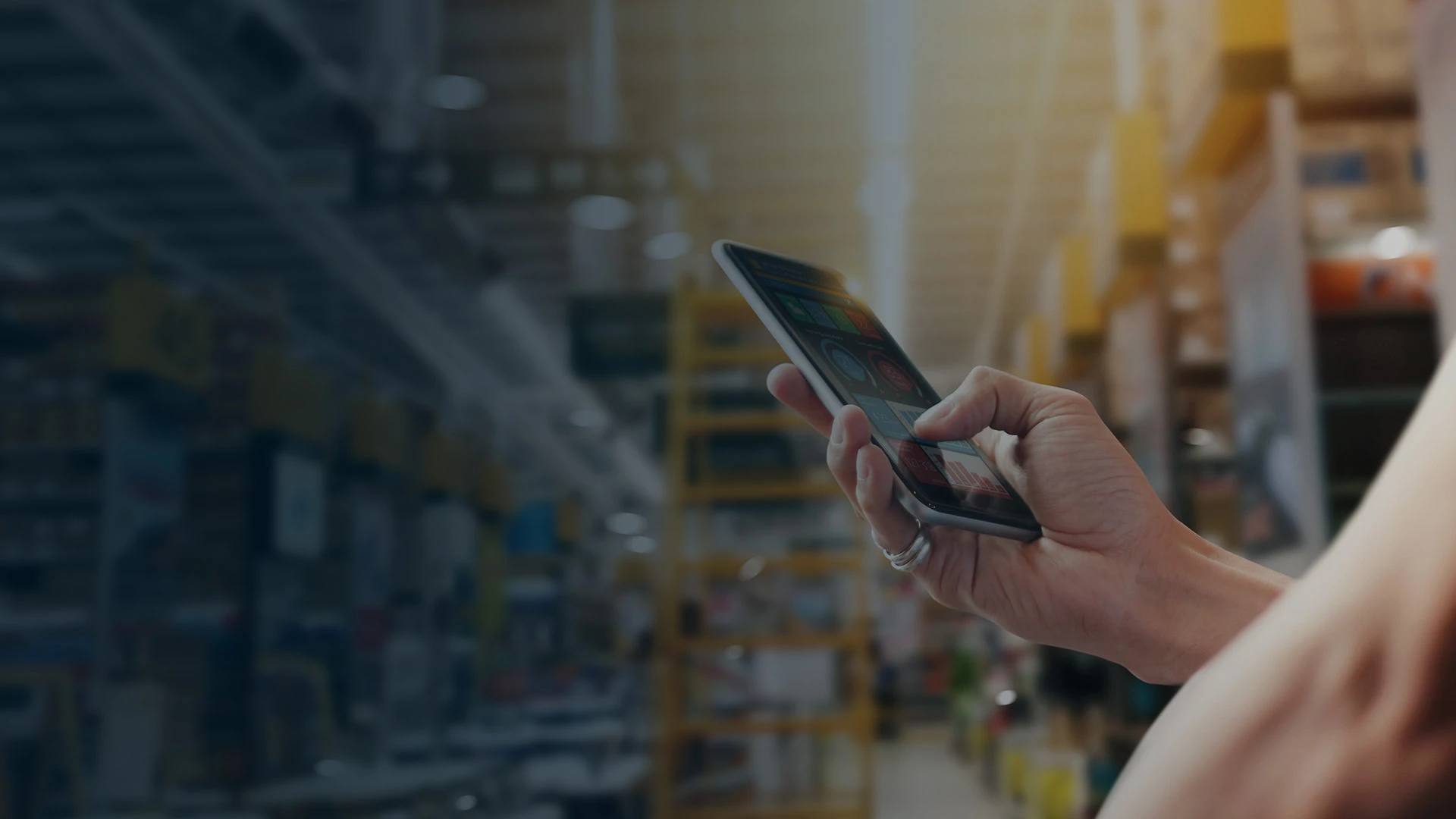 mobility solutions page banner of hand holding smart phone while in warehouse aisle